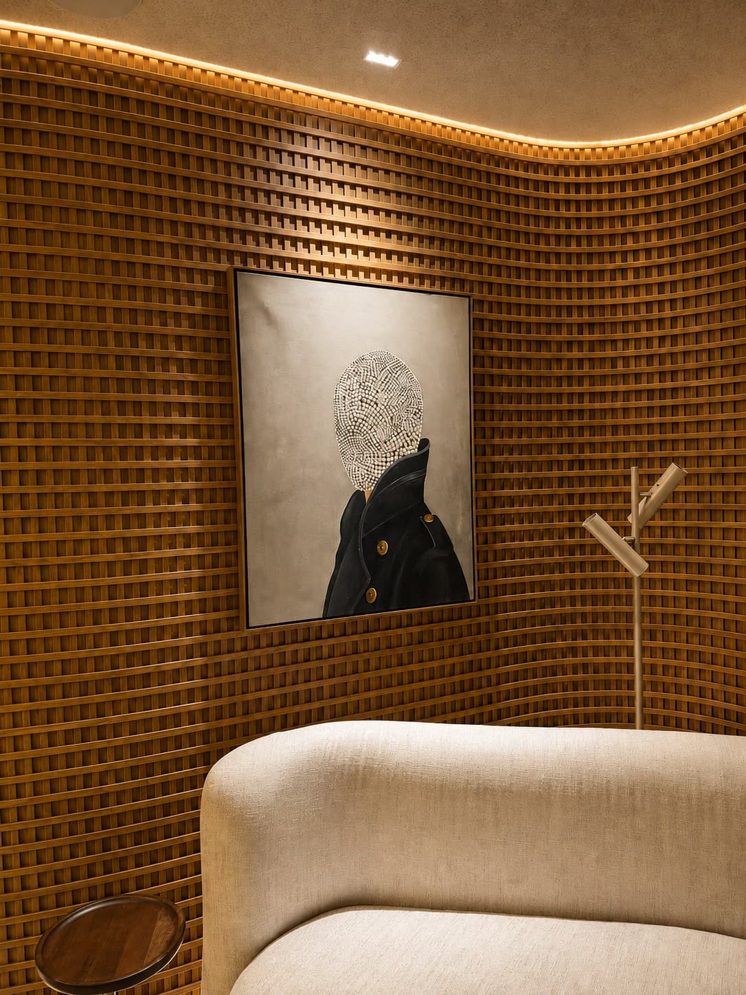 Obra de Ivan Hansen instalada na parede curva de muxarabi da Arco Clinic: figura de casaco escuro com rosto coberto por mosaico de contas