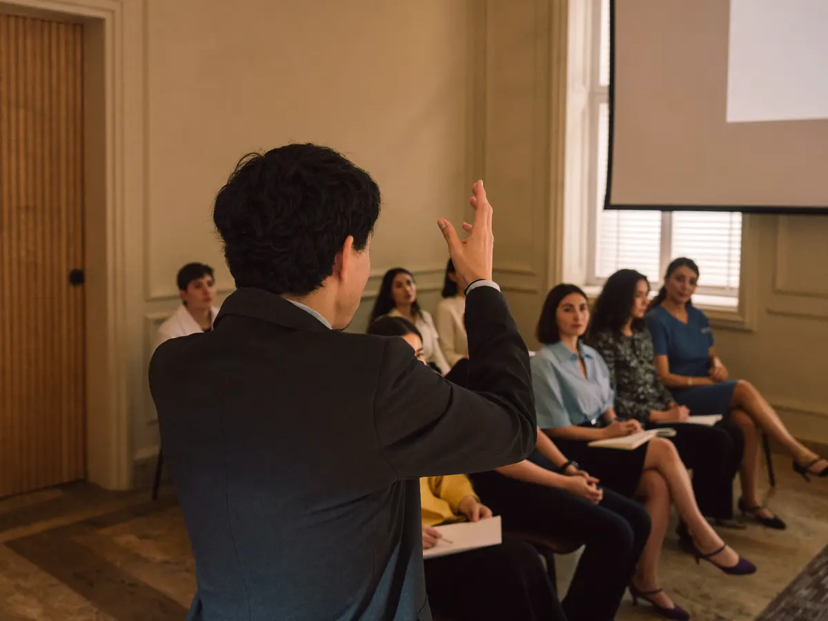 Médico conduciendo un workshop para un pequeño grupo de profesionales en una sala de tonos cálidos