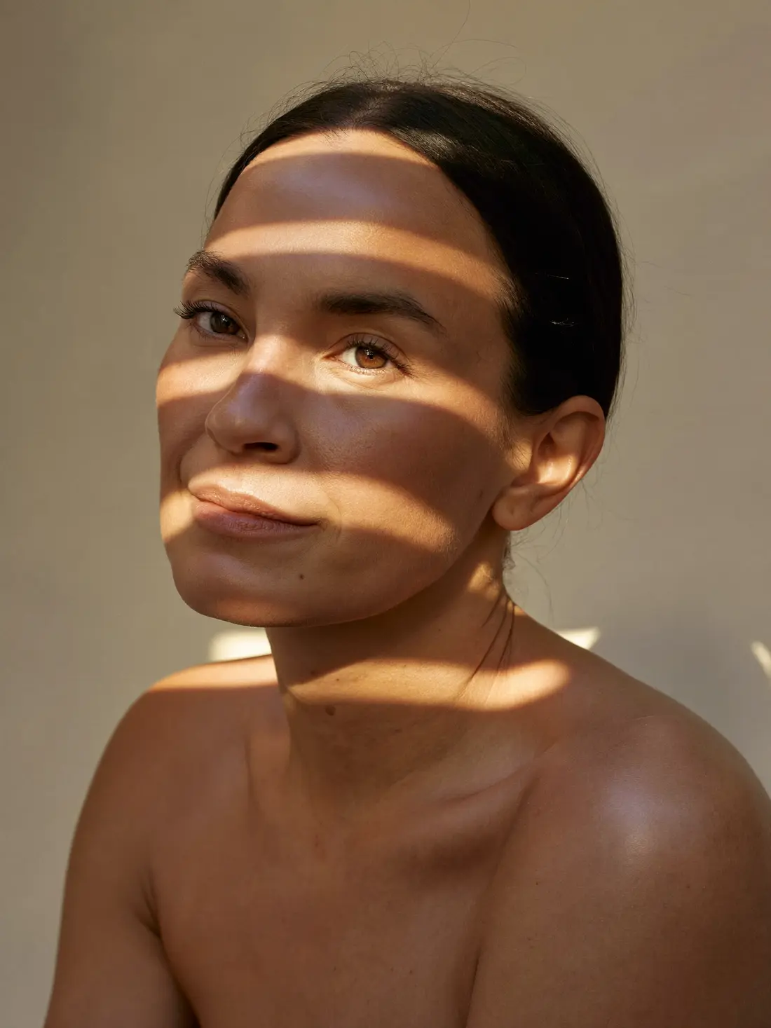 Retrato editorial de mujer con bandas suaves de luz y sombra marcando los tercios del rostro